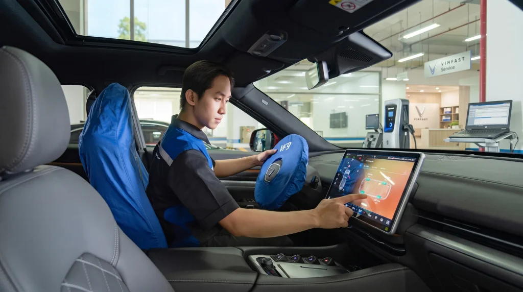 Kỹ thuật viên đang ngồi trong khoang lái xe VinFast VF 9 thao tác kiểm tra trên màn hình cảm ứng trung tâm.