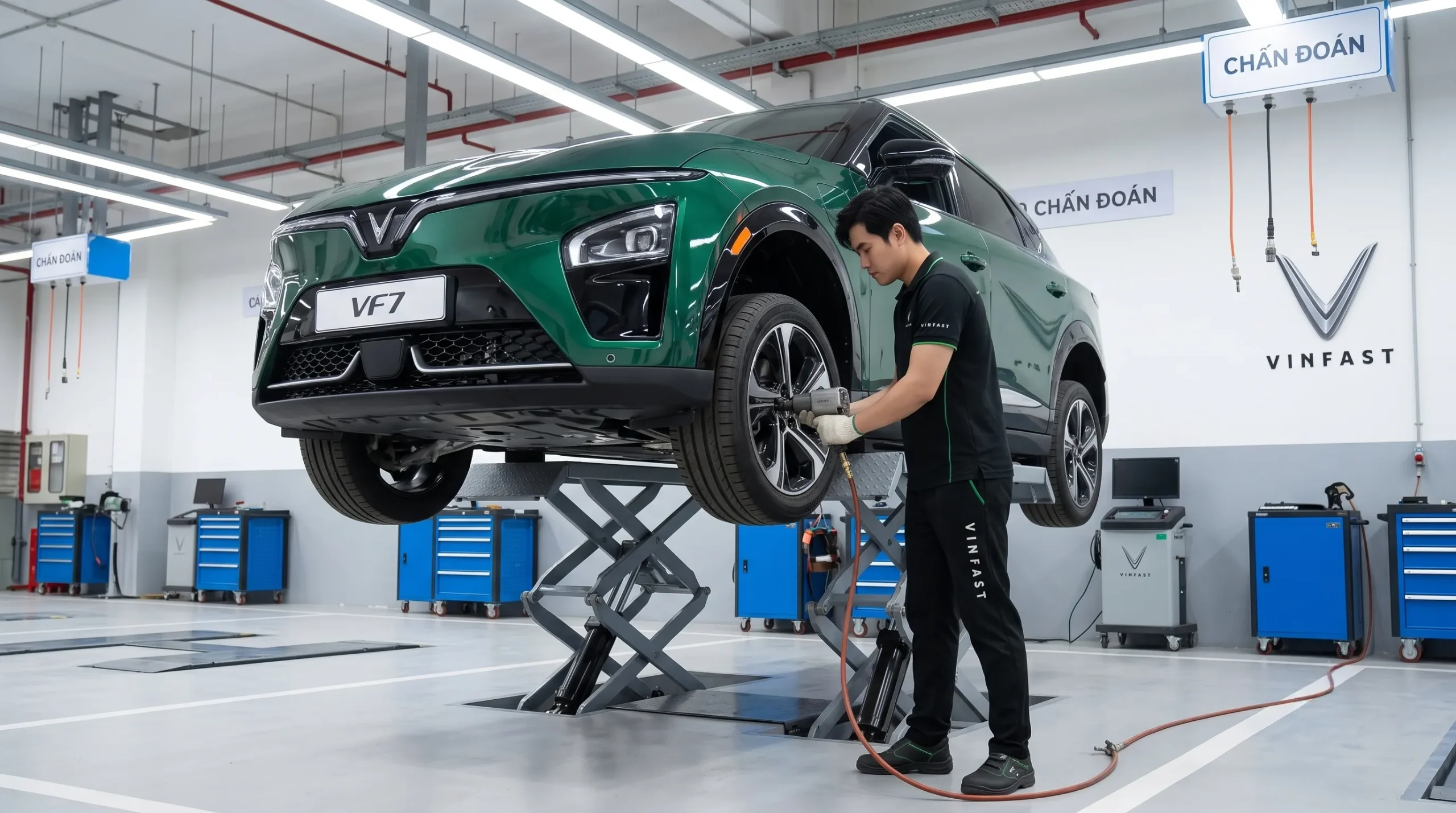 Kỹ thuật viên VinFast đang đứng thao tác kiểm tra lốp và gầm xe điện VF 7 màu xanh trên cầu nâng.